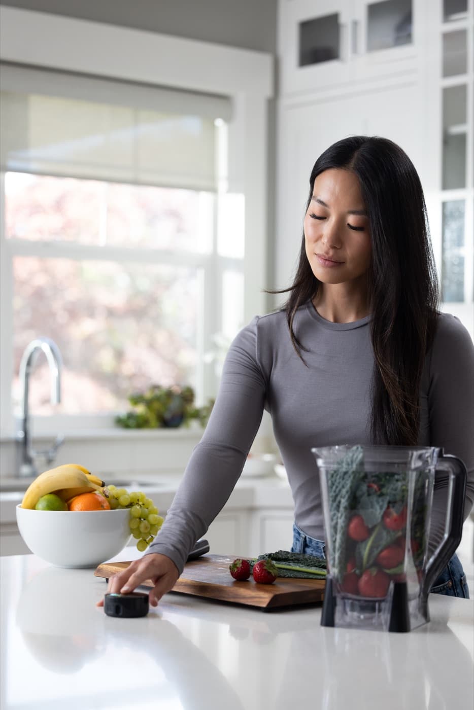 A woman at a kitchen counter resting a fingertip on the Prysm iO scanner